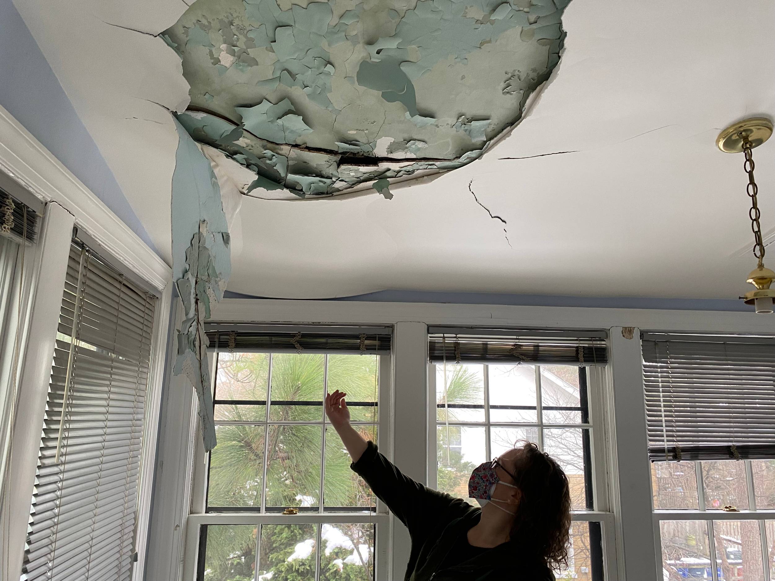Photo showing a hole in the pain, several feet wide, and cracking ceiling materials within the hole.