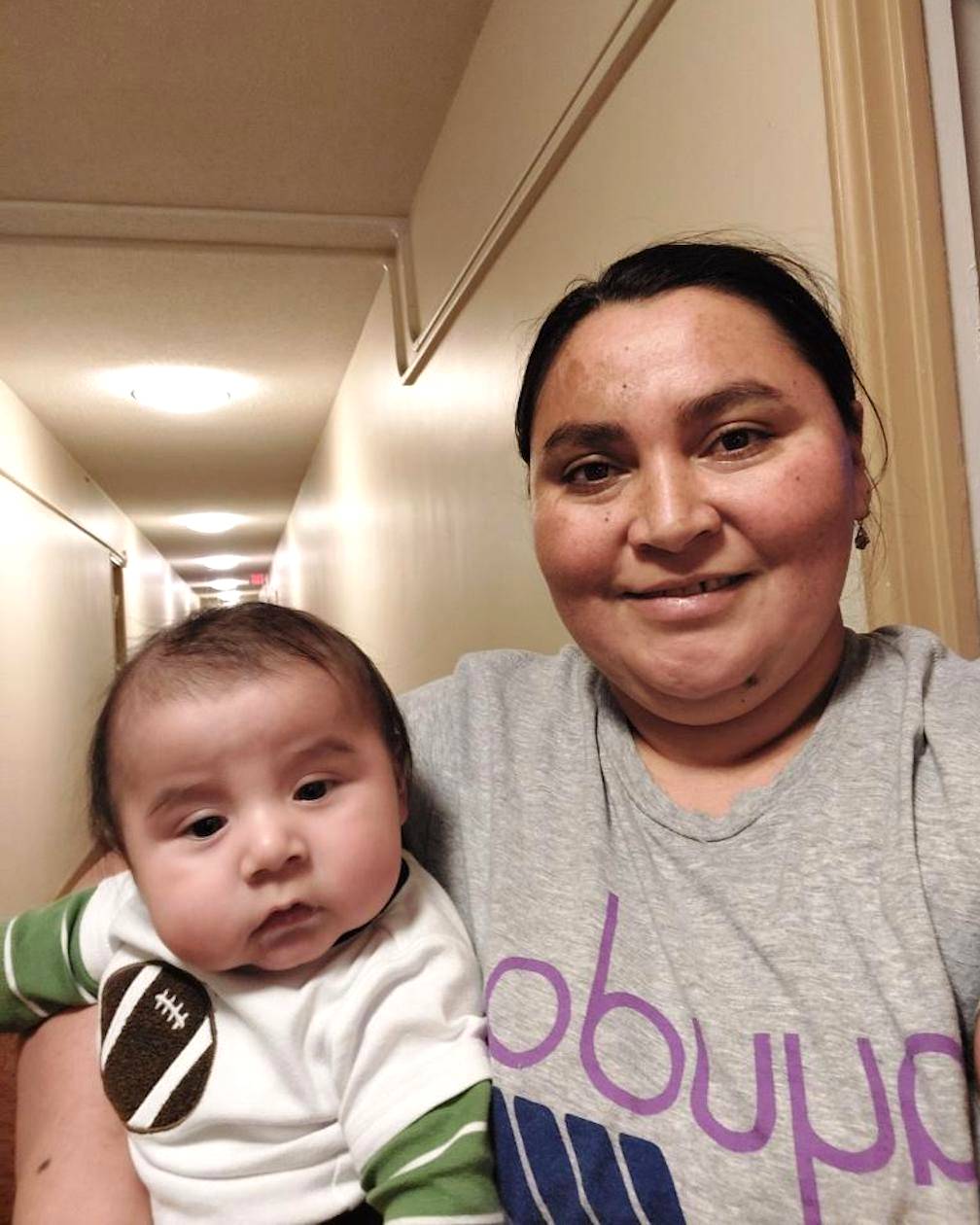Photo of a woman holding her young child in a hallway.