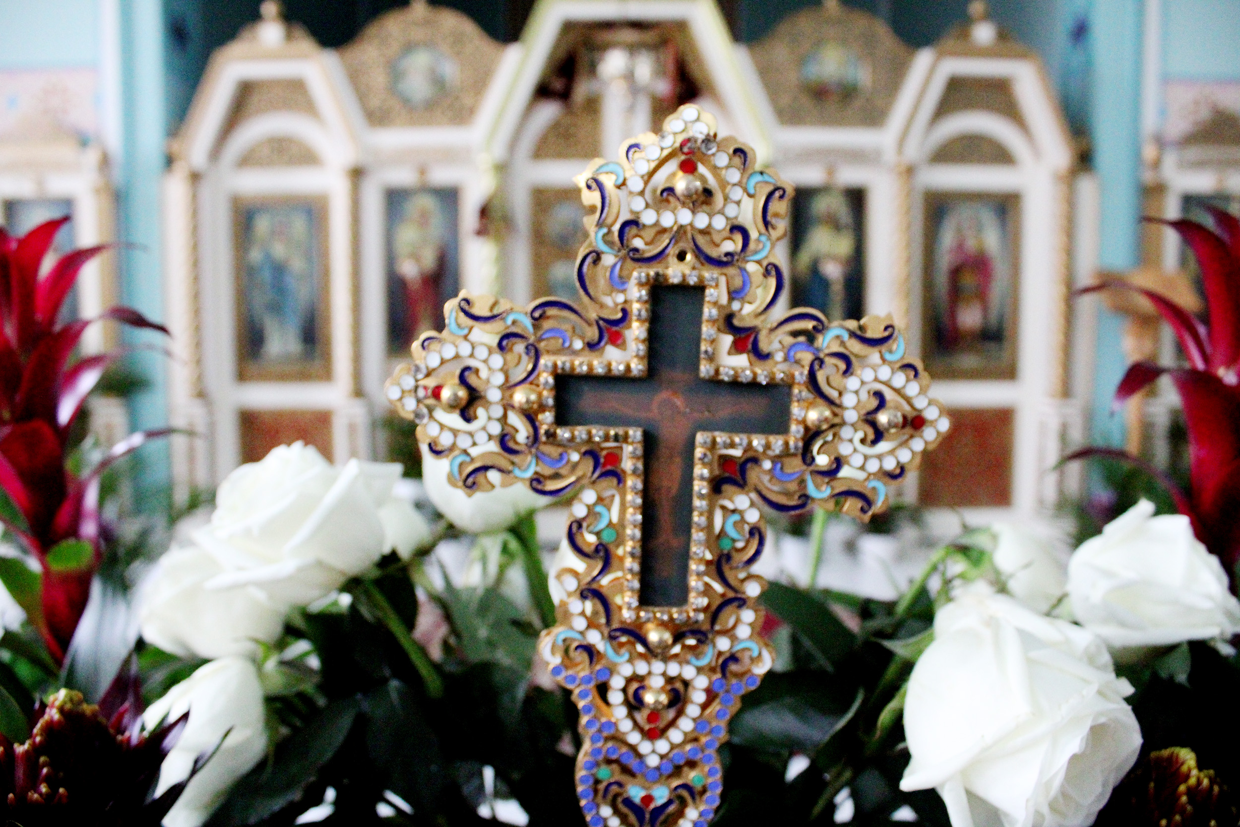 Photo of an ornate cross, displayed within a flower arrangement, within the Ukrainian orthodox church.