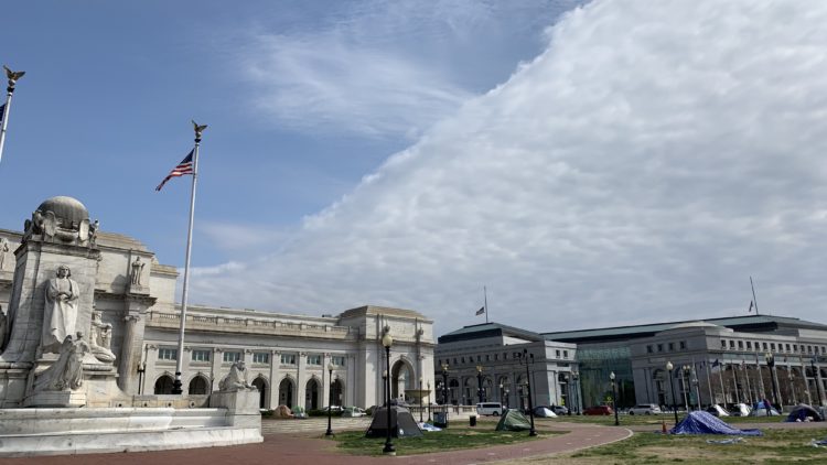 Photo of several tents, and a statue, in front of Union Station