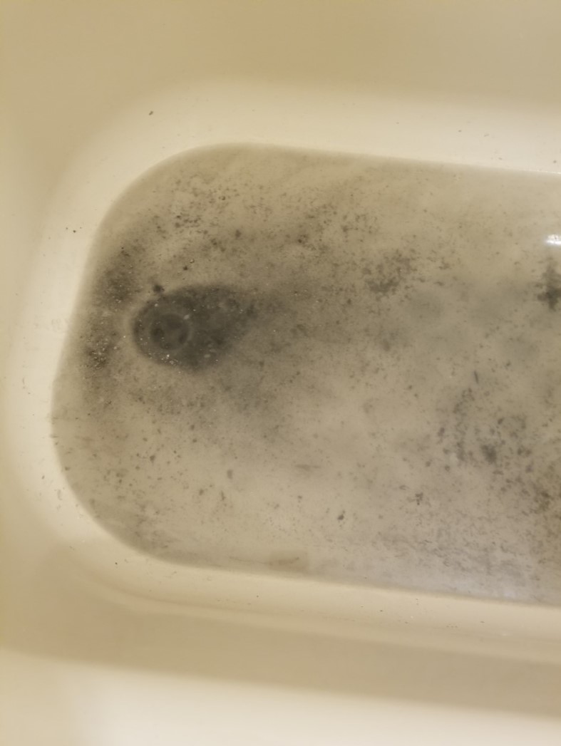 Photo of dirty water sitting in a tub. The bathtub is in an apartment afforded through the Rapid Rehousing program.
