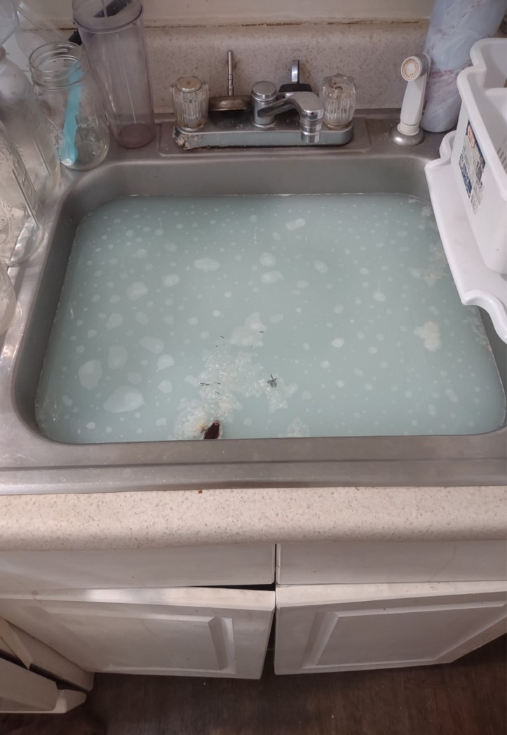 Photo of a sink, filled with blue-tinted foam and bubbles.