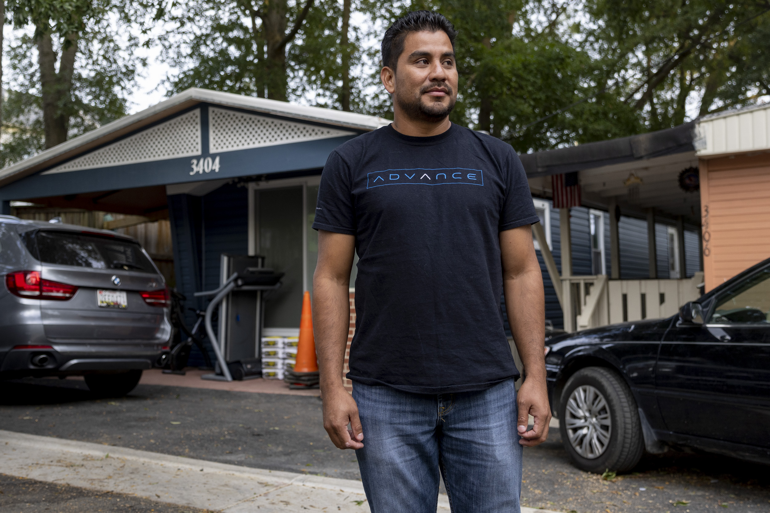 Photo of a many standing in front of a mobile home and a parked car