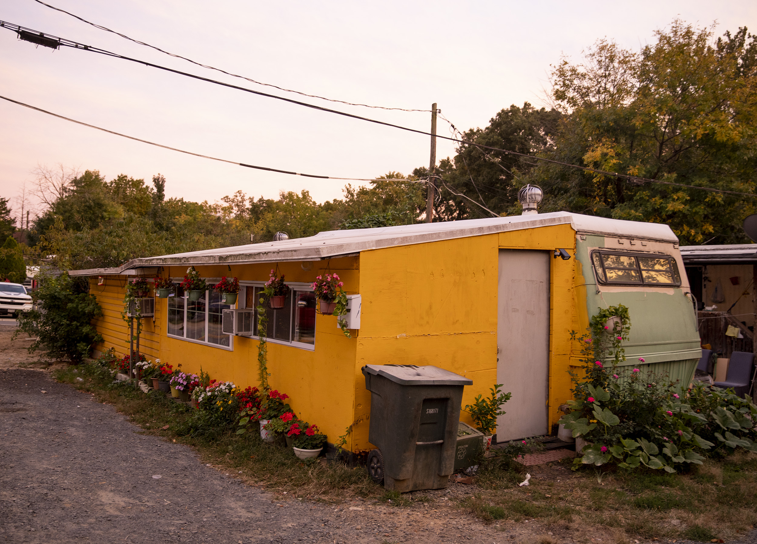 A long yellow shed-like structure sitting next to a light green manufactured home