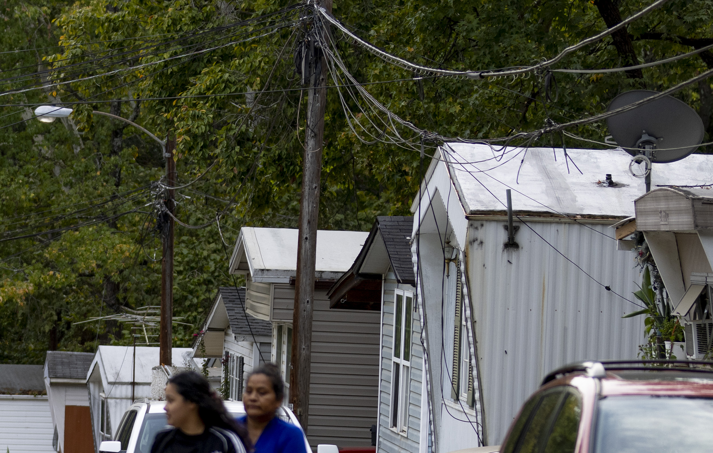 Photo of a row of small manufactured houses, where the lines between power polls sag low and close to the structures.