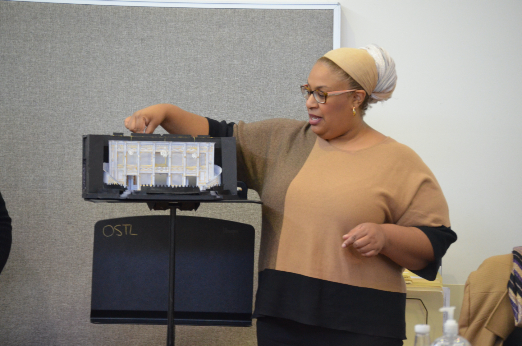 Photo of Sharif standing next to set model on a stand, giving direction