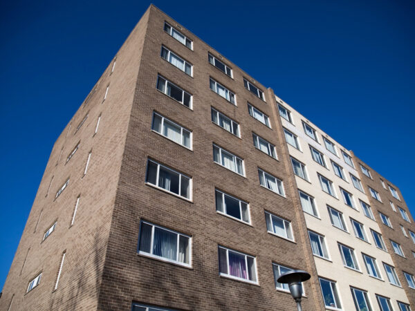 Photo of an apartment building with blue sky behind it.