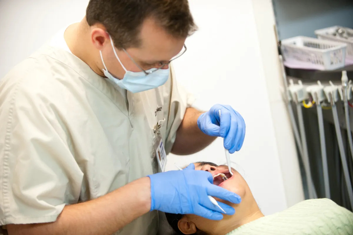 Photo of a dental patient whose mouth is being examined by an oral health professional