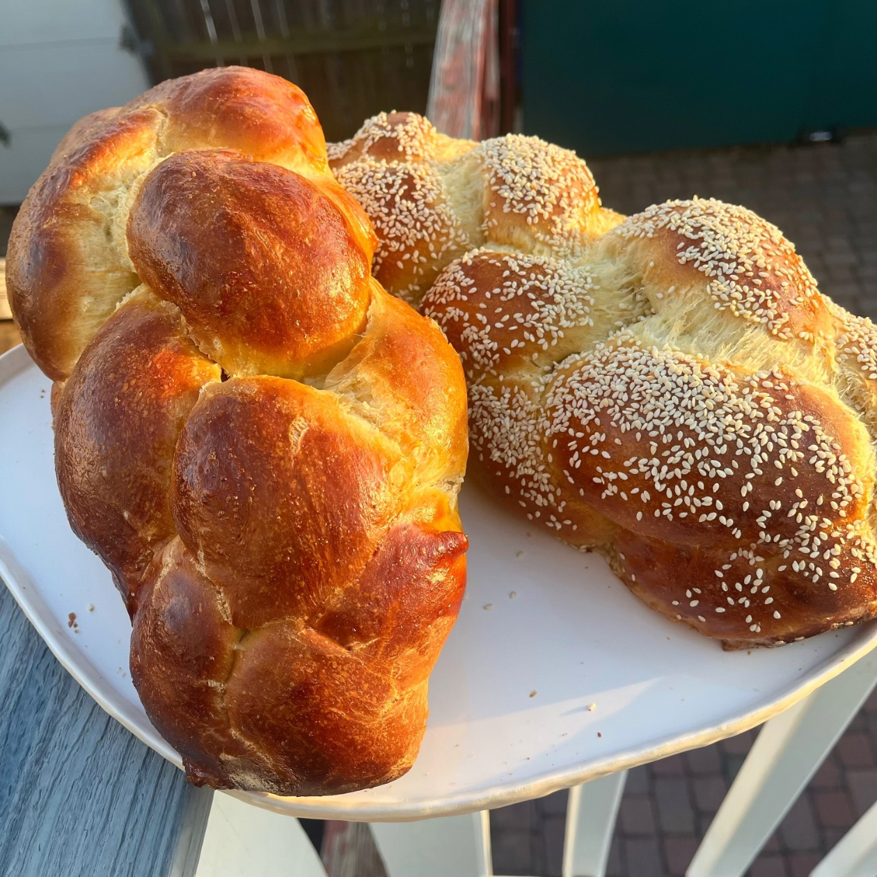 Close up of two challah loaves, one plain and the other topped with sesame seeds