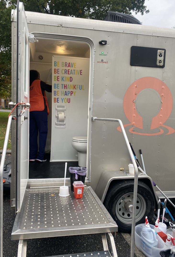 Photo looking through the entrance of the mobile shower unit. The wall next to a toilet says "Be Brave, Be Creative, Be Kind, Be Thankful, Be Happy, Be You"