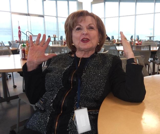 Photo of Gutiérrez gesturing with her hands while sitting at a table in a school room.